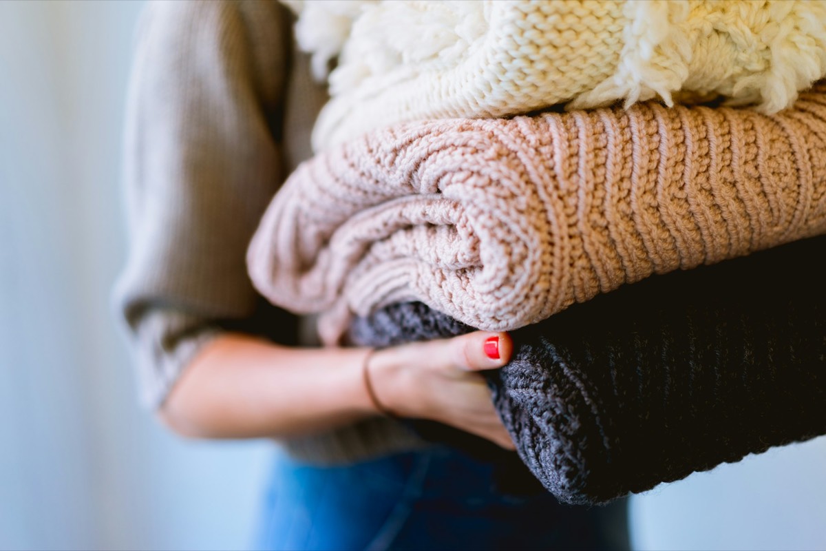 Arms carrying a stack of folded knitwear