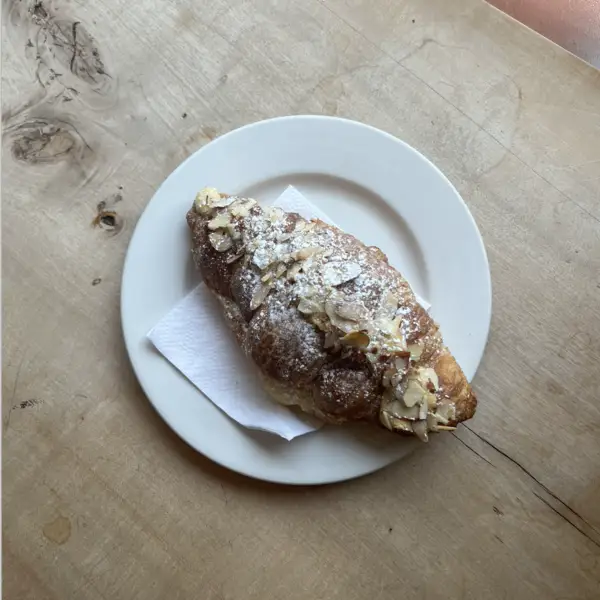 An almond croissant dusted with icing sugar and sliced almonds