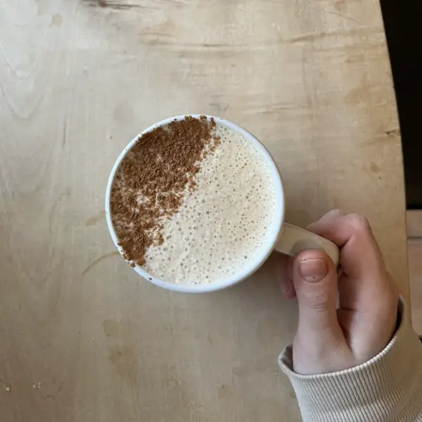 A chai latte dusted with cinnamon on one half