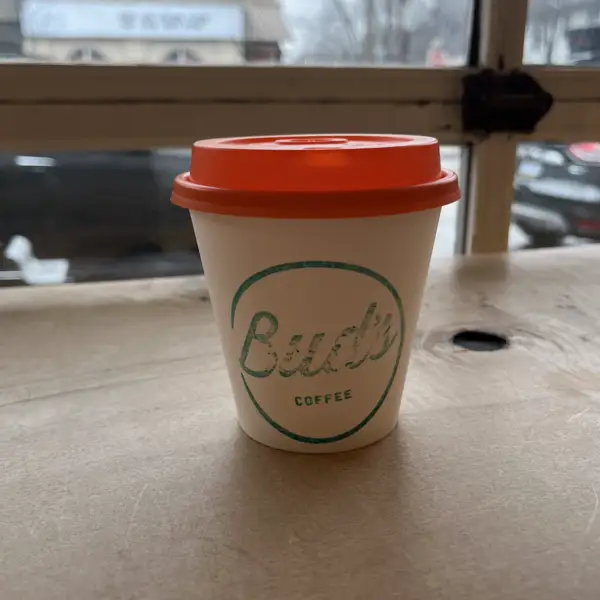 A Bud's takeaway cup with an orange lid by the front window