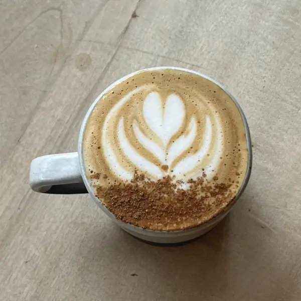 A flat white with a tulip pour in a grey cup, from above