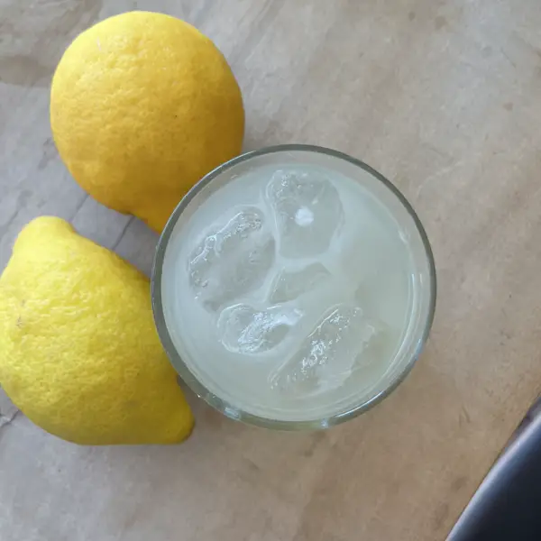 An iced lemonade from above, next to two lemons