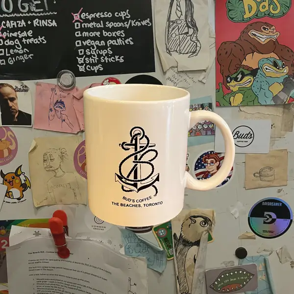 A cream 12 oz mug with an anchor print reading Bud's Coffee, the Beaches, Toronto
