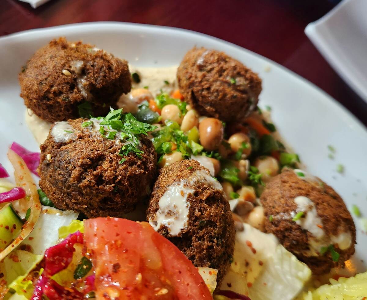 Close-up of falafel with tahini over chickpeas, salad and tomato