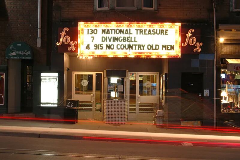 The Fox Theatre marquee at night, with red fox signs on Queen St E