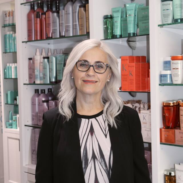 Carm, Co-owner, in front of the salon’s product wall
