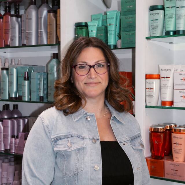 Diana, Sr. Stylist, in front of the salon’s product wall