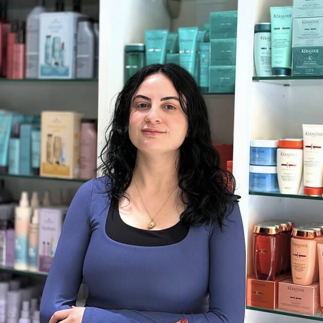 Jada, Apprentice, in front of the salon’s product wall
