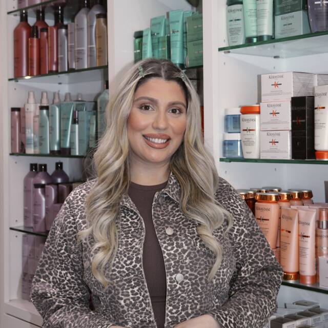 Mariam, Stylist, in front of the salon’s product wall