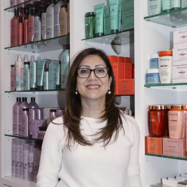 Nilo, Sr. Stylist, in front of the salon’s product wall