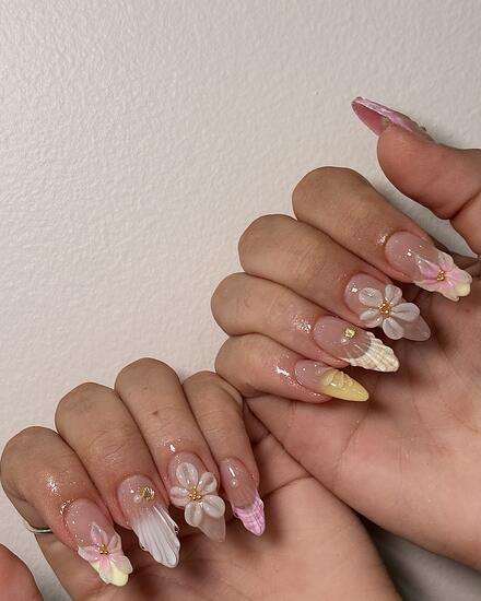 Clear pink nails with white and pink 3D flowers, a sculpted shell and a yellow accent