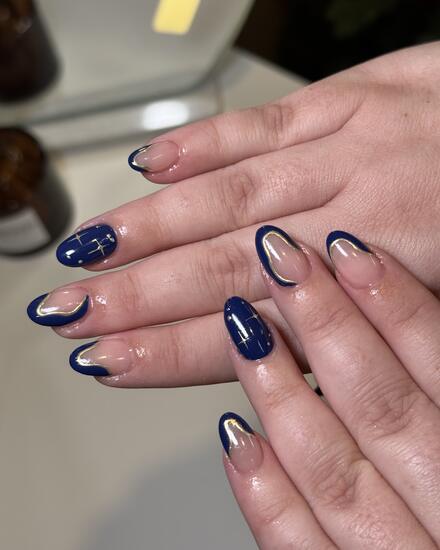 Almond nails with navy French tips, navy accents and small silver stars