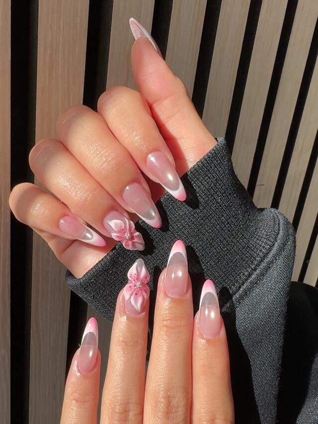 Long almond nails with soft pink French tips and two sculpted 3D pink blossoms