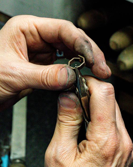 A jeweller's hands working on a small piece at the bench