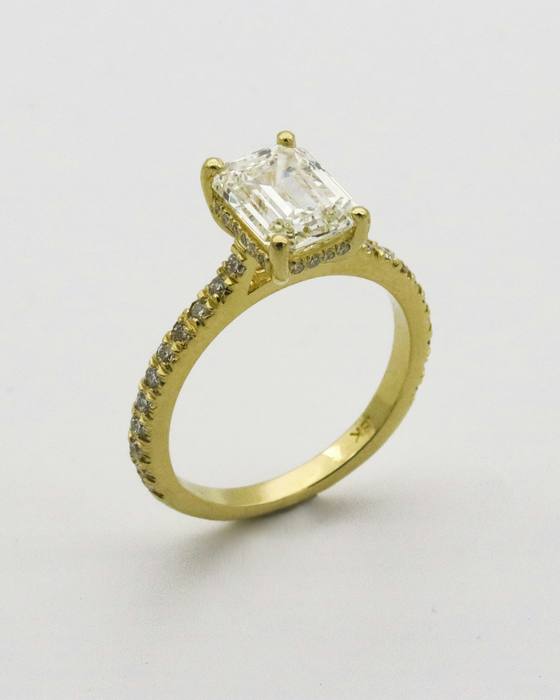 A yellow gold engagement ring with an emerald-cut stone