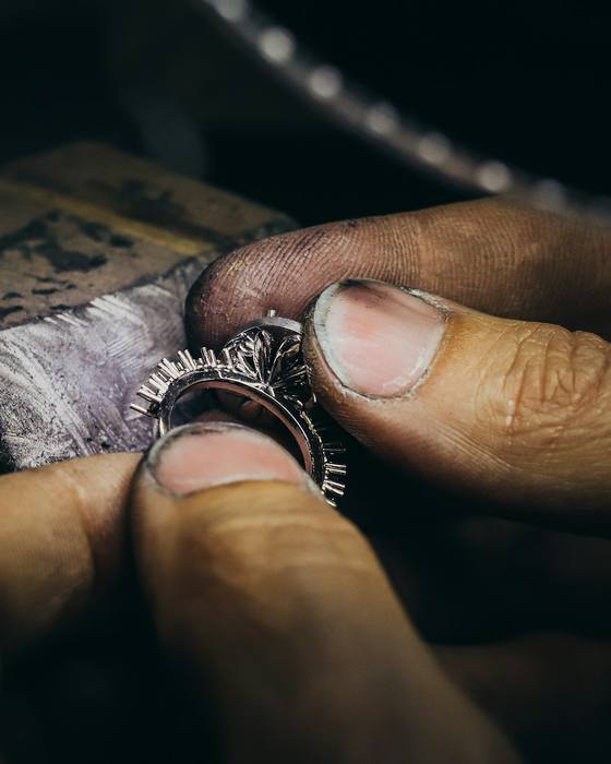 Hands holding a ring against a jeweller's bench pin