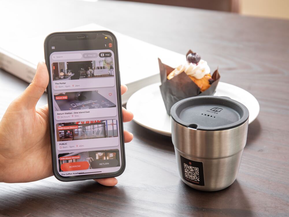 A Muuse cup beside a muffin, with the Muuse app open on a phone