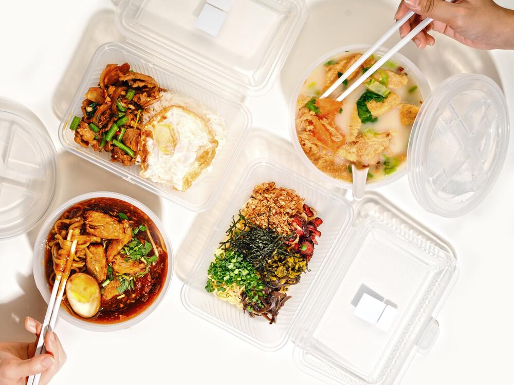 Noodles, curry and rice dishes in clear reusable Muuse food boxes, seen from above
