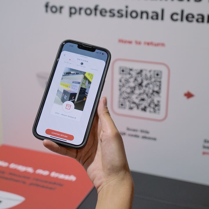 A phone scanning the QR code on a Muuse return point poster