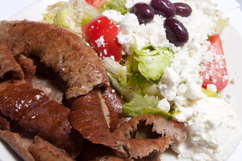 Gyros slices beside a Greek salad with feta and kalamata olives
