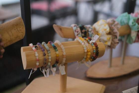 Stone-bead bracelets in amethyst, jade and amber stacked on a wooden display bar