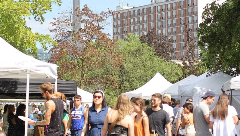 Crowds on a sunny afternoon between rows of white market tents